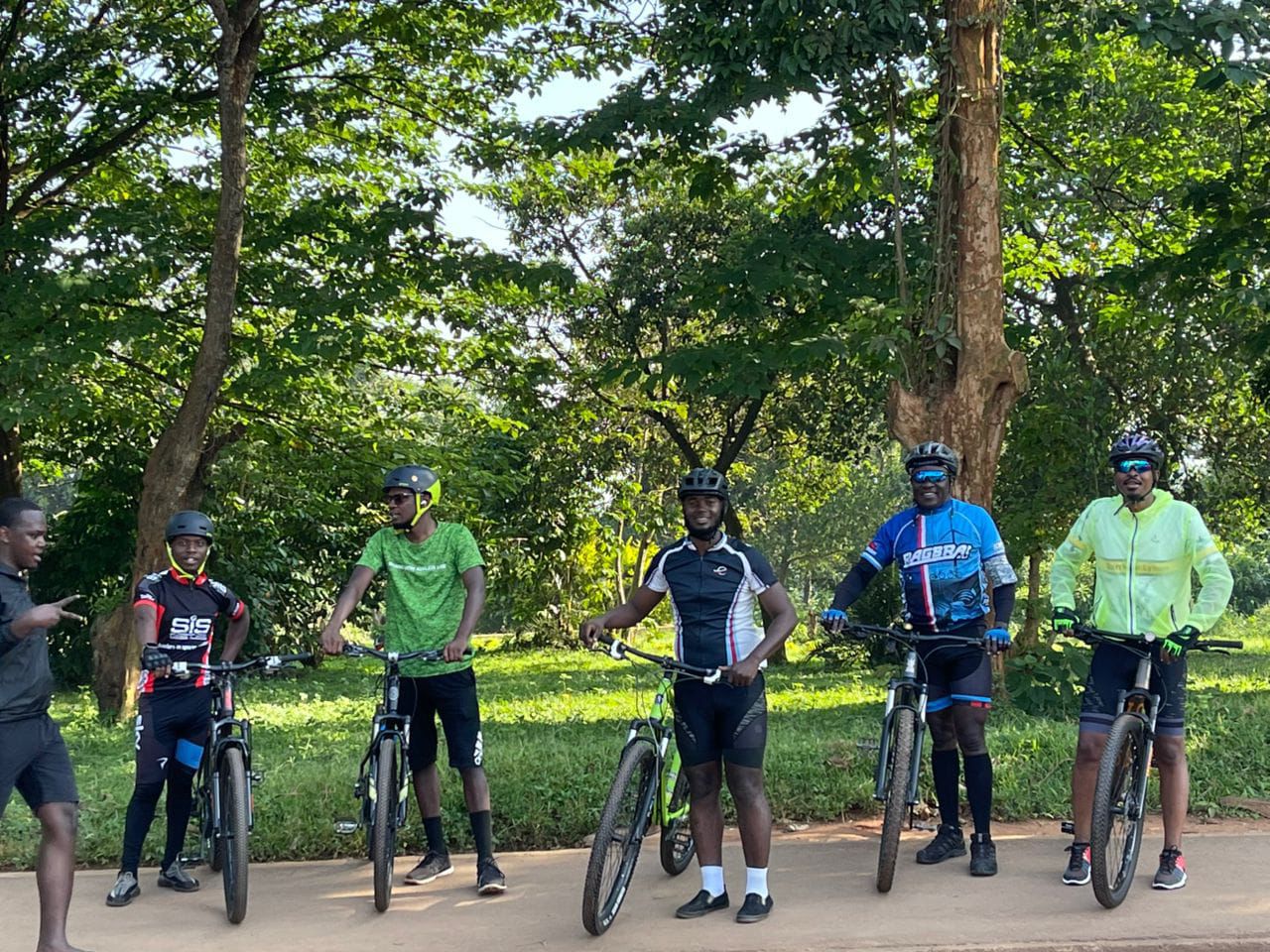 Group of six riders resting under trees along a park path