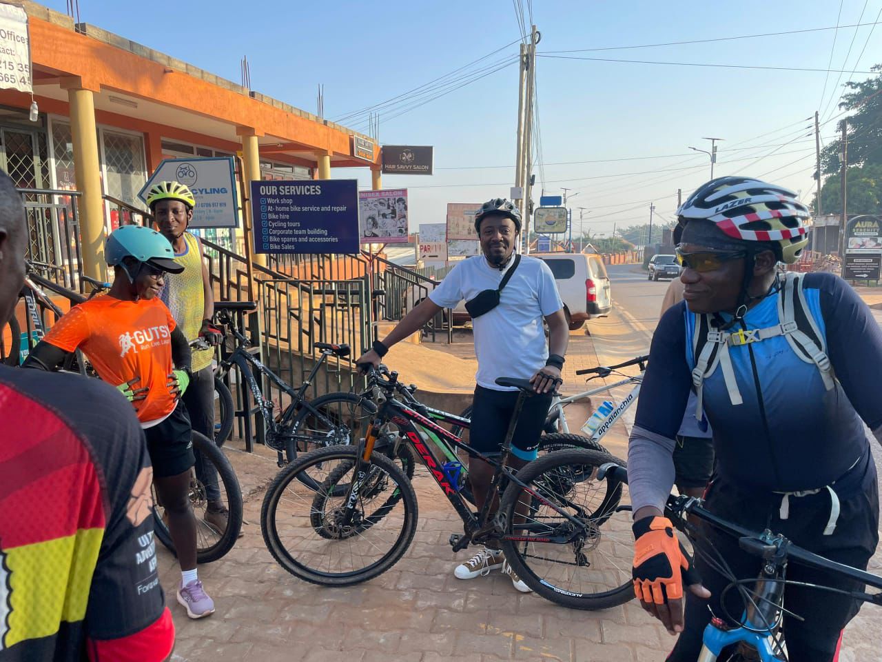 Group of riders outside the Ngalo shopfront beside the "Our Services" signboard