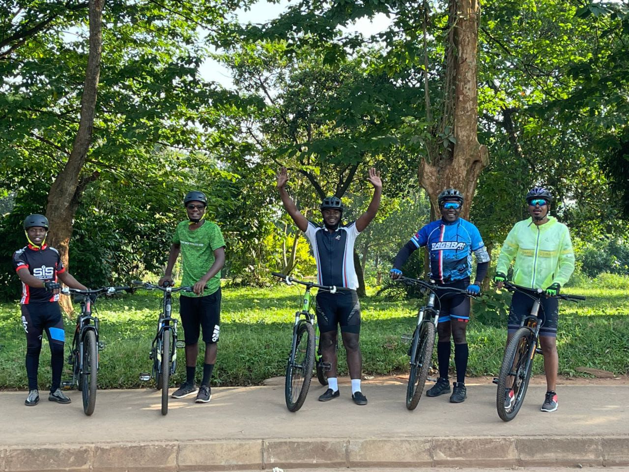 Group of five riders resting under trees on a forest path