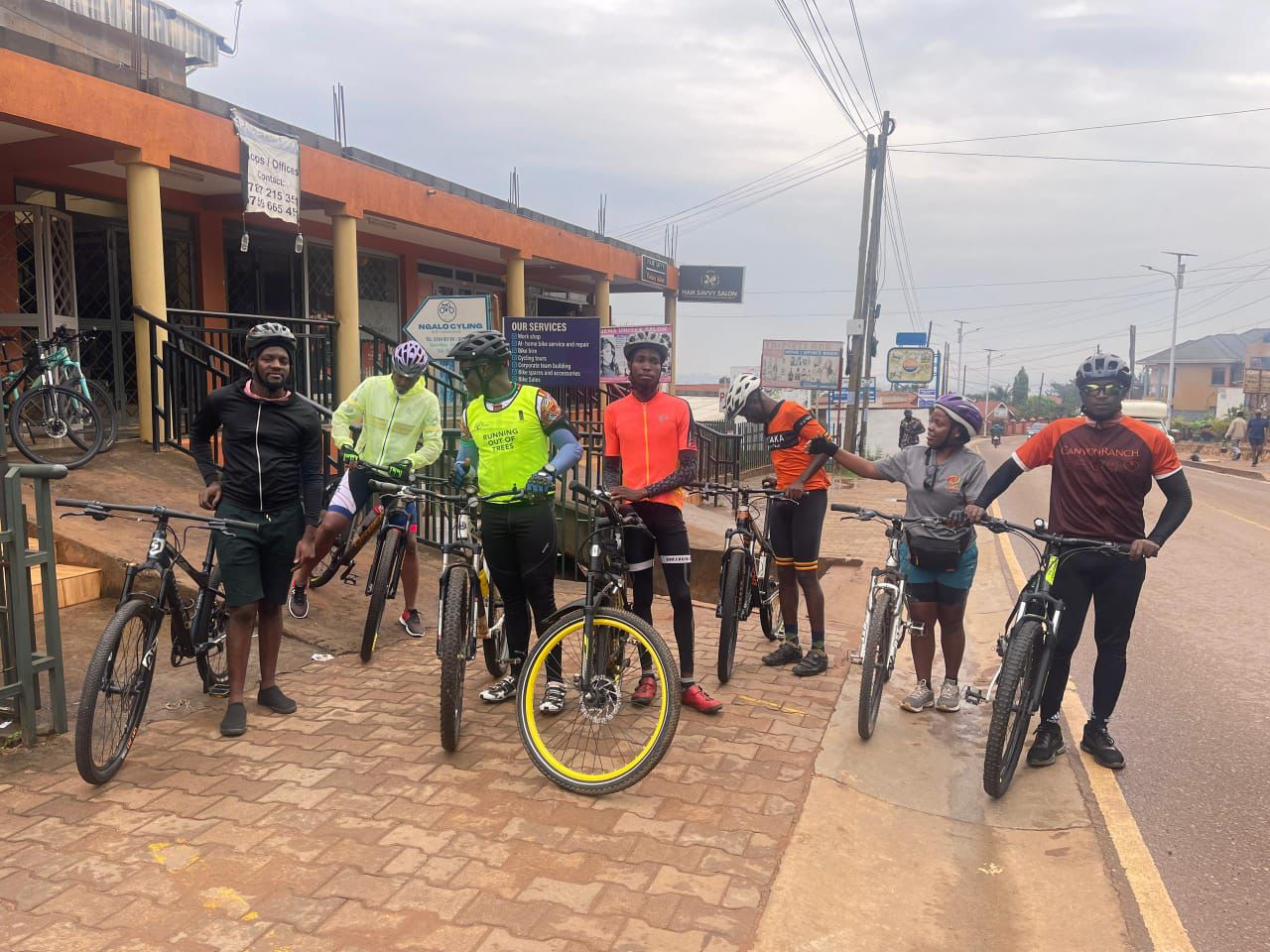 Group of eight cyclists outside the Ngalo shopfront and services board